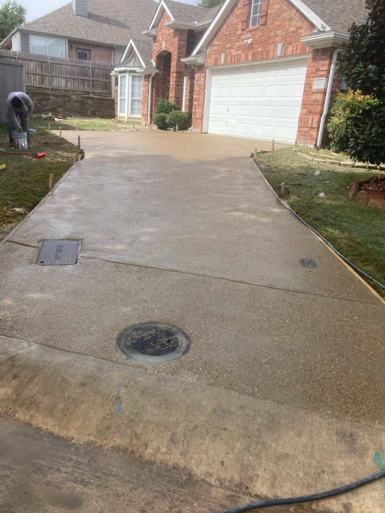 Concrete driveway with flooding water leading to brick house garage and landscaped yard