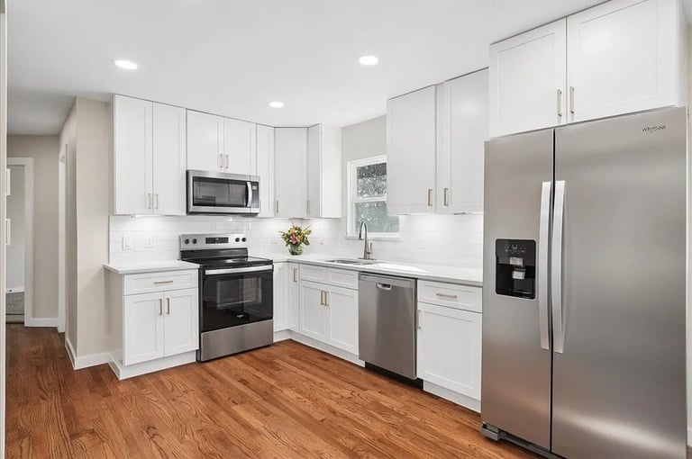 Modern kitchen with white cabinetry, stainless steel appliances, and hardwood flooring