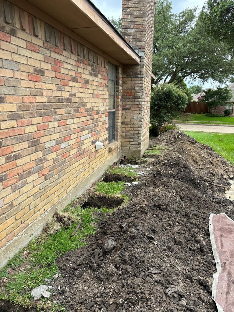 Brick house exterior with newly mulched garden bed along foundation and residential lawn visible in background